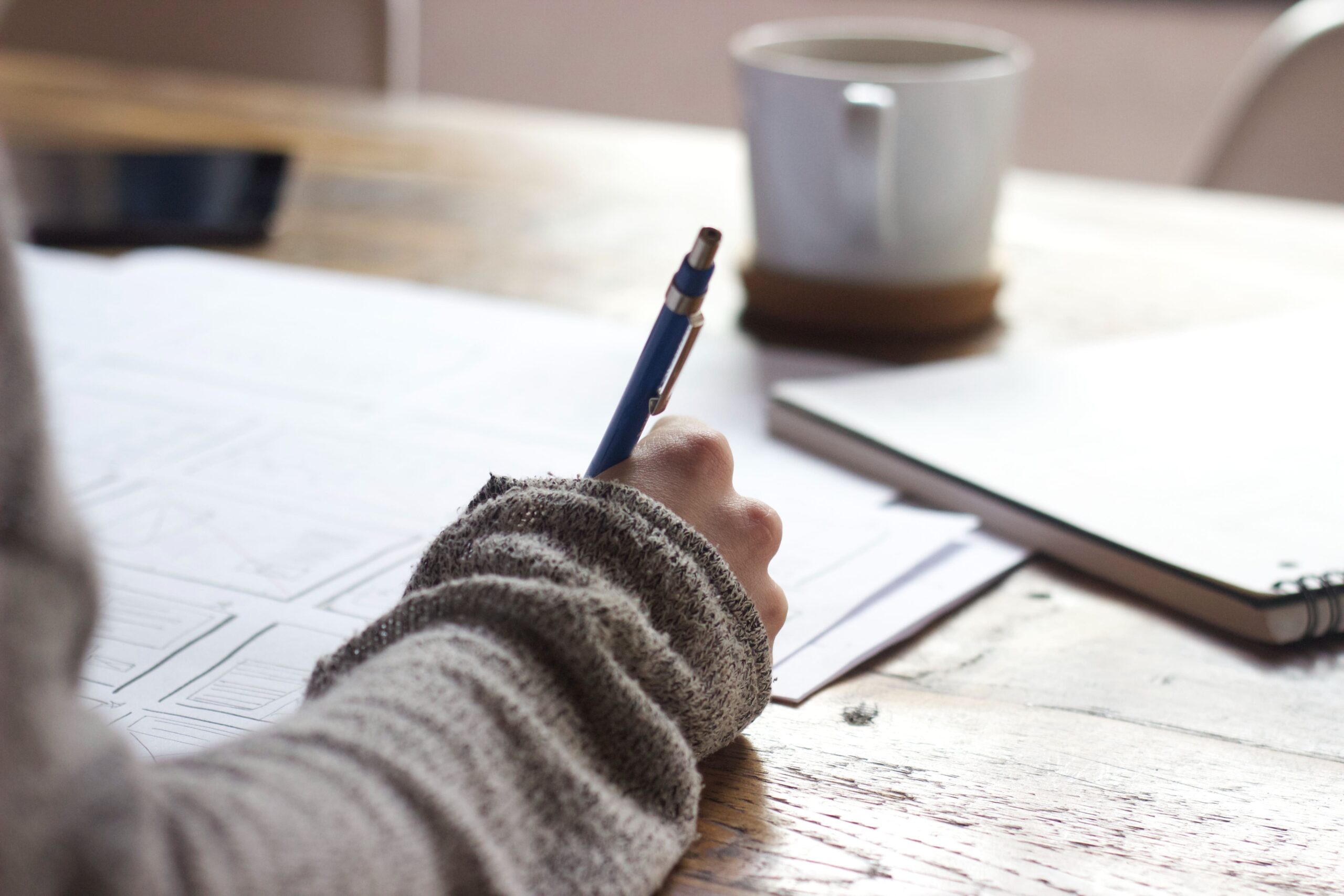 picture of woman writing in diary on desk planning June 2023 calendar for Koala Digitals social media content calendar