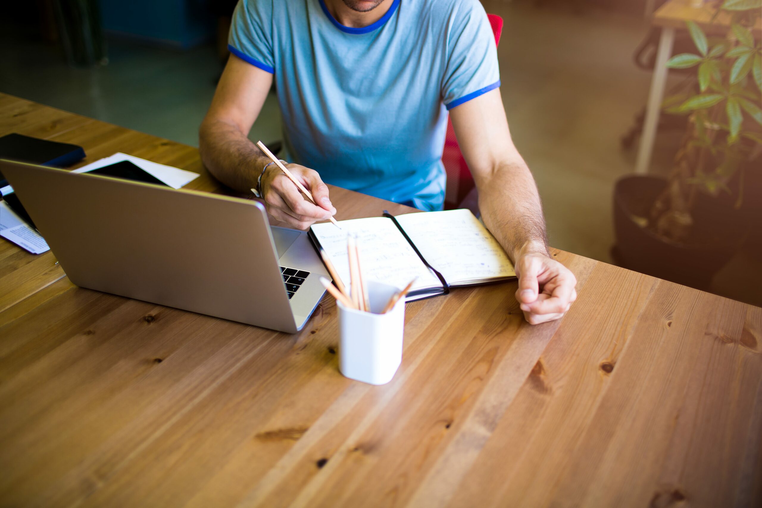 Man sat at table writing a content calendar with help from the Koala Digital social media content calendar November edition 2023!